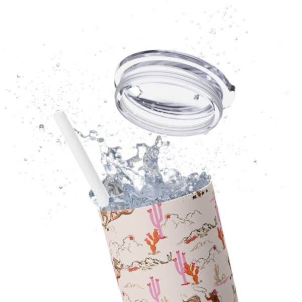 Close-up of the Cowgirl Skinny Tumbler with the top off, splashing liquid, showcasing the vibrant design of a bucking horse, pink cacti, and mountain motifs in bold colors.